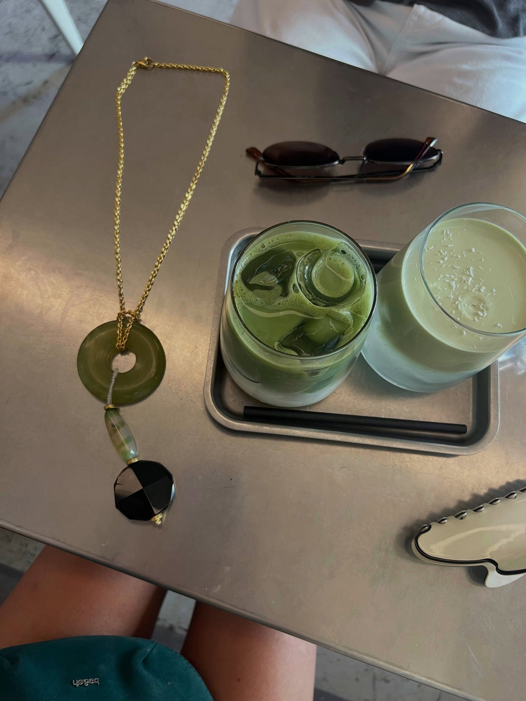 Collar Donut Pistacho de jade y ónix sobre una mesa junto a dos bebidas – TideStone
